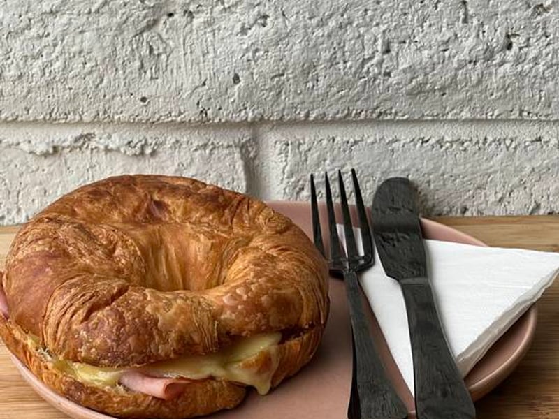 A ham and cheese croissant on a pink plate